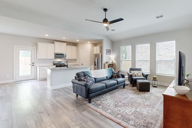 living room featuring lofted ceiling, ceiling fan, and light wood-type flooring