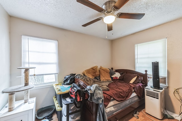 bedroom with a textured ceiling, ceiling fan, and wood-type flooring