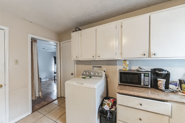 laundry area with washer / clothes dryer, a textured ceiling, and light tile patterned floors