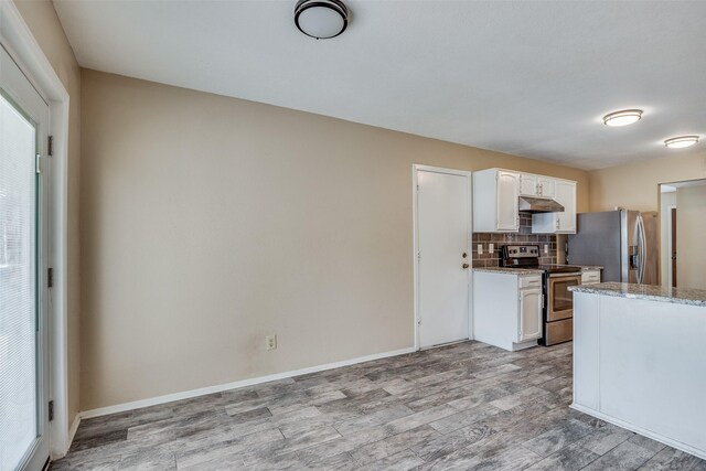 kitchen with stainless steel appliances, white cabinets, light stone counters, light hardwood / wood-style floors, and backsplash