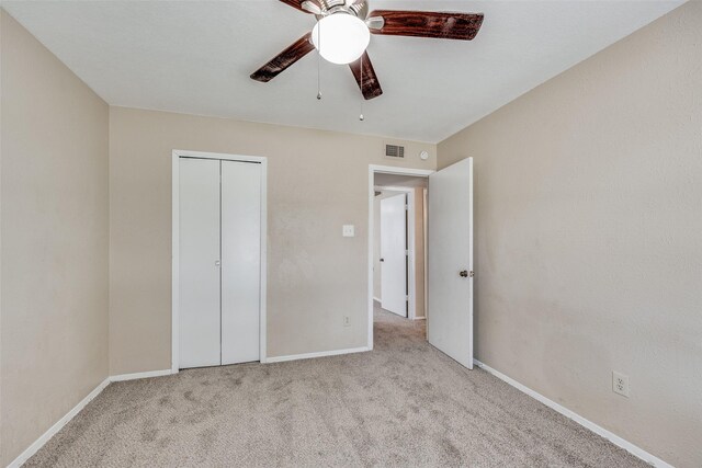 unfurnished bedroom with light carpet, a closet, and ceiling fan