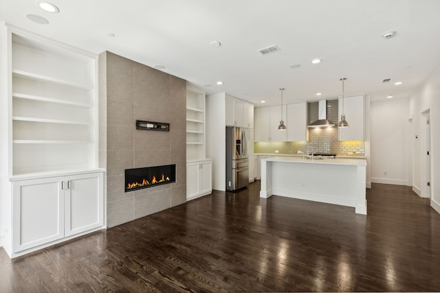 unfurnished living room featuring built in features, dark wood-type flooring, and a tile fireplace