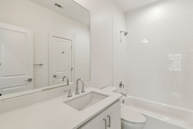 full bathroom featuring vanity, tiled shower / bath combo, and toilet