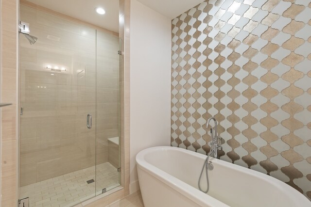 full bathroom with a shower stall, a freestanding tub, and recessed lighting