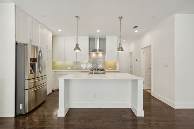 kitchen with wall chimney range hood, light countertops, decorative backsplash, stainless steel refrigerator with ice dispenser, and white cabinets