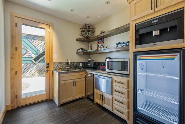 kitchen with light brown cabinetry, sink, appliances with stainless steel finishes, and dark tile patterned floors