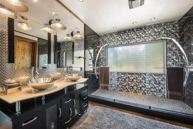 bathroom with dual vanity, a shower with door, and backsplash