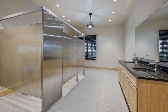 kitchen with dark stone counters, light brown cabinetry, decorative light fixtures, and sink