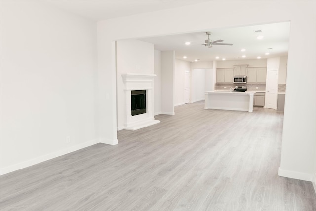 unfurnished living room with light wood-type flooring and ceiling fan