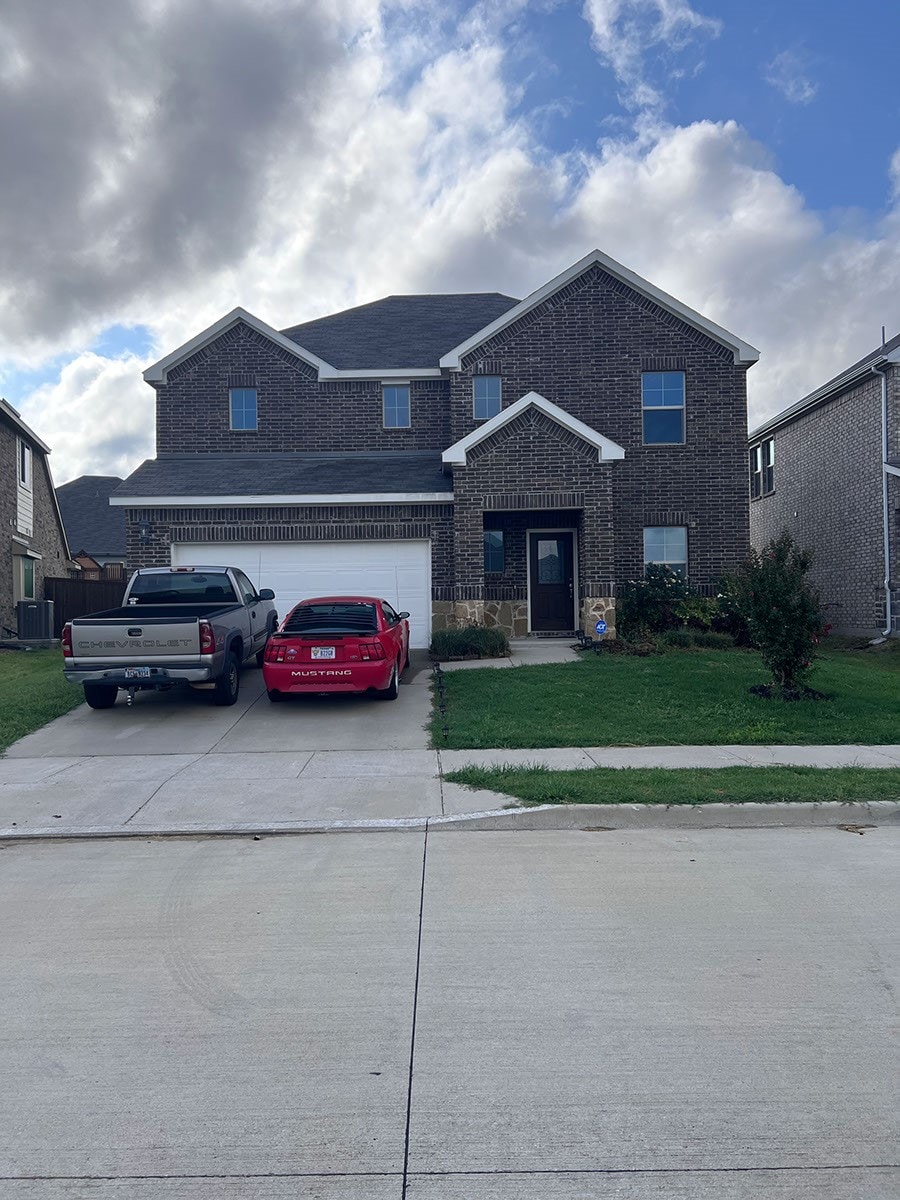 view of front of property with a garage, central AC unit, and a front lawn