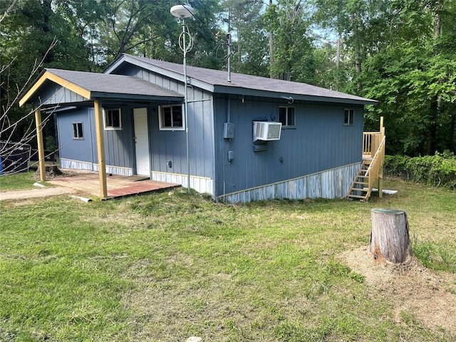 view of front of home with a wall mounted air conditioner and a front yard