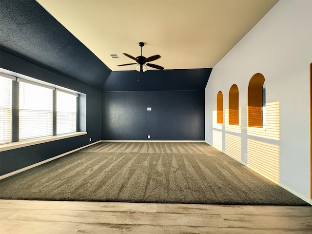 empty room featuring ceiling fan, carpet floors, and vaulted ceiling