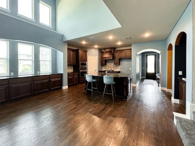 kitchen with a wealth of natural light, dark hardwood / wood-style floors, stainless steel appliances, and a kitchen island with sink