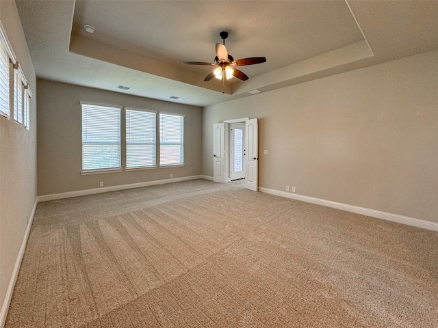 carpeted empty room featuring a tray ceiling and ceiling fan