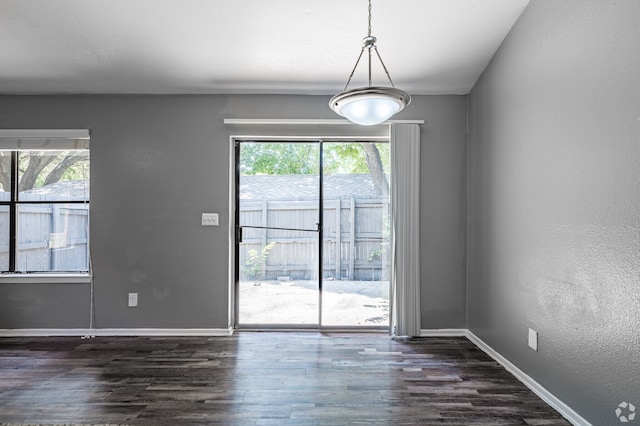 unfurnished dining area featuring dark wood-type flooring