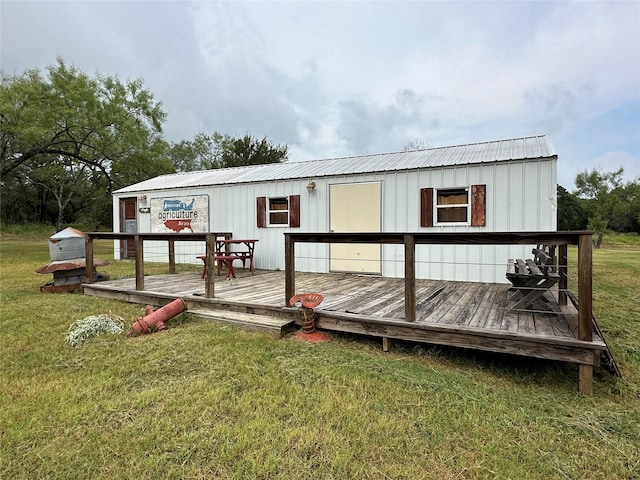 rear view of property with metal roof, a lawn, and a wooden deck