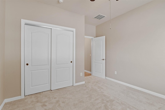 unfurnished bedroom featuring ceiling fan, light colored carpet, and a closet