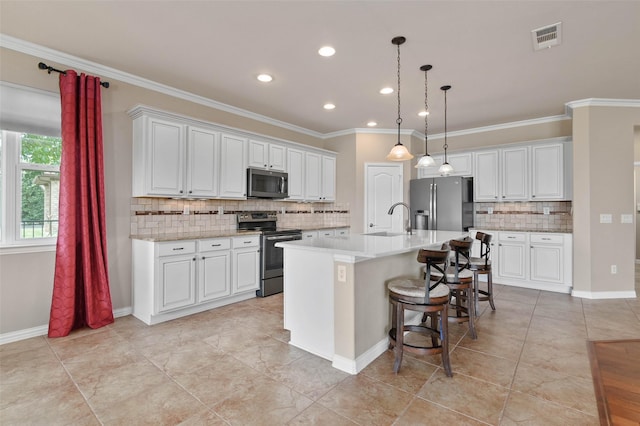 kitchen featuring white cabinetry, pendant lighting, a center island with sink, and appliances with stainless steel finishes