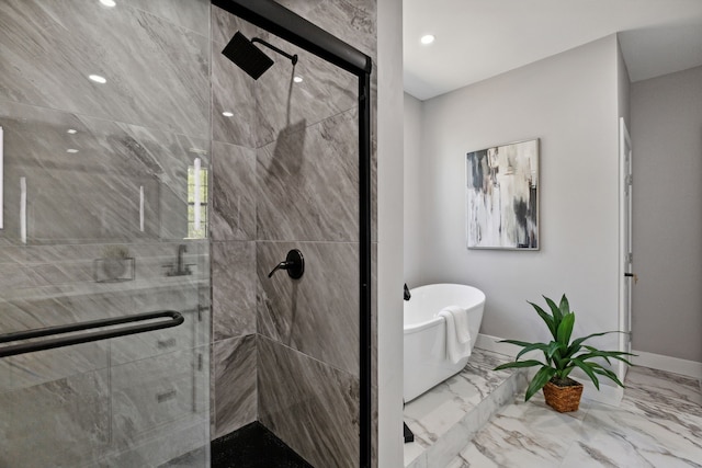 bathroom featuring marble finish floor, a freestanding tub, a shower stall, and baseboards