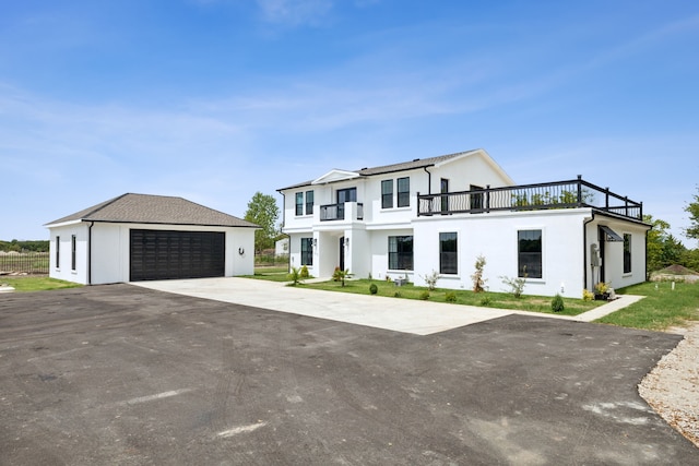 view of front of property featuring a balcony, stucco siding, a detached garage, and an outdoor structure