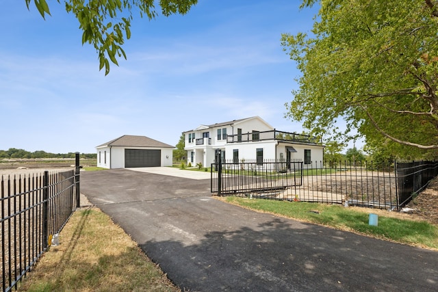 view of front facade with stucco siding, a detached garage, fence, and an outbuilding