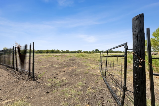 view of gate with fence and a rural view