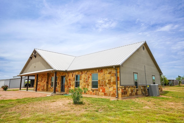 back of house with cooling unit, a carport, and a yard