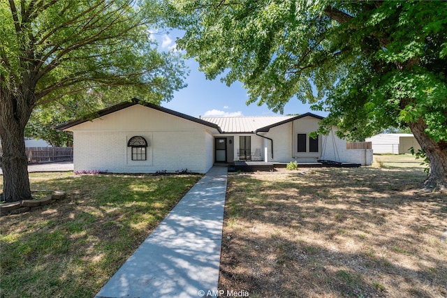 ranch-style home featuring fence, metal roof, and brick siding