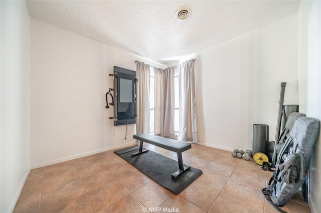 exercise room with visible vents, a textured ceiling, and baseboards
