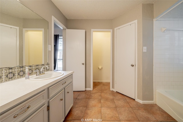 bathroom with backsplash, a textured ceiling, vanity, baseboards, and tile patterned floors