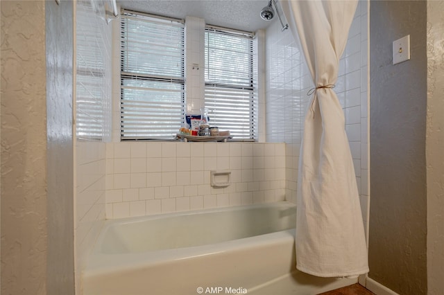 bathroom featuring a shower with curtain, a textured wall, and a bathtub