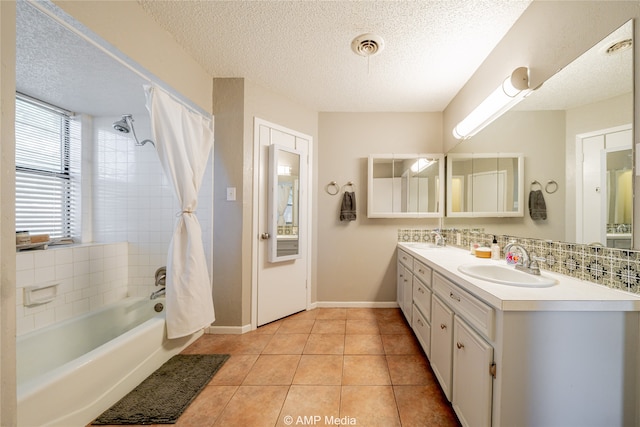 bathroom with tile patterned flooring, a textured ceiling, and dual bowl vanity