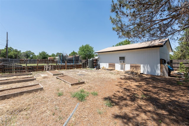 view of yard featuring fence, a trampoline, and a vegetable garden