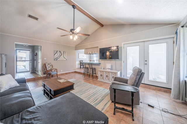 living room with lofted ceiling with beams, french doors, light tile patterned floors, a textured ceiling, and ceiling fan