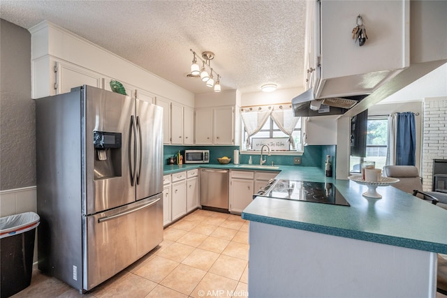 kitchen with a textured ceiling, appliances with stainless steel finishes, a sink, a peninsula, and white cabinetry