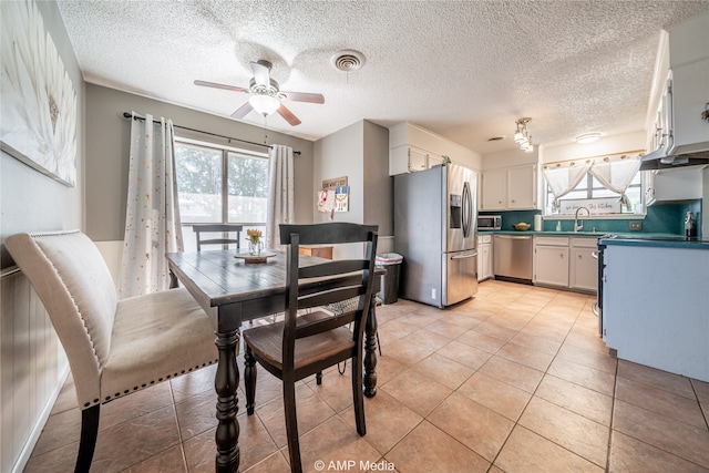 dining area featuring sink, a textured ceiling, ceiling fan, and light tile patterned floors