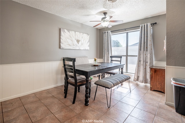 tiled dining space with a textured ceiling and ceiling fan