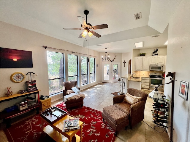 tiled living room with a tray ceiling and ceiling fan with notable chandelier