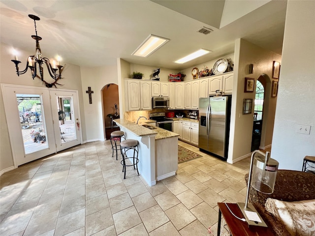 kitchen with sink, kitchen peninsula, hanging light fixtures, stainless steel appliances, and light stone counters