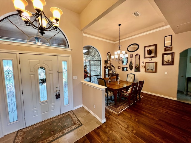 entrance foyer with an inviting chandelier, crown molding, wood-type flooring, and a wealth of natural light