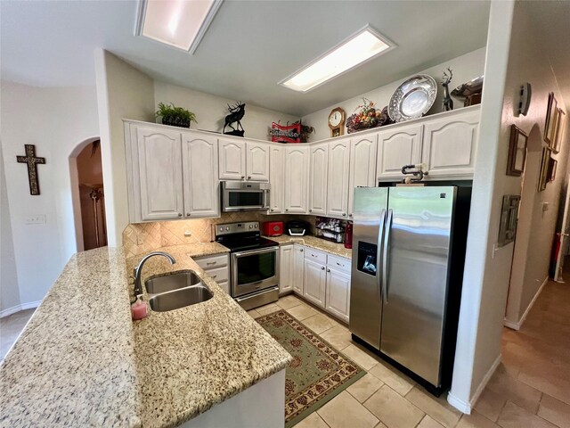 kitchen featuring sink, appliances with stainless steel finishes, kitchen peninsula, and white cabinetry