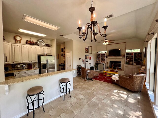 kitchen featuring white cabinets, light stone countertops, a kitchen bar, stainless steel refrigerator with ice dispenser, and decorative light fixtures