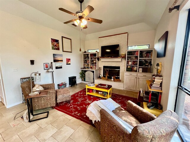 living room featuring vaulted ceiling, a fireplace, and ceiling fan