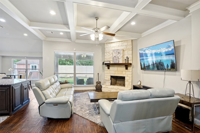 living room featuring ceiling fan, dark hardwood / wood-style flooring, beam ceiling, coffered ceiling, and a stone fireplace