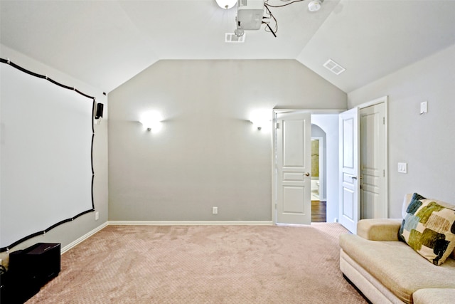 cinema room with light carpet and vaulted ceiling