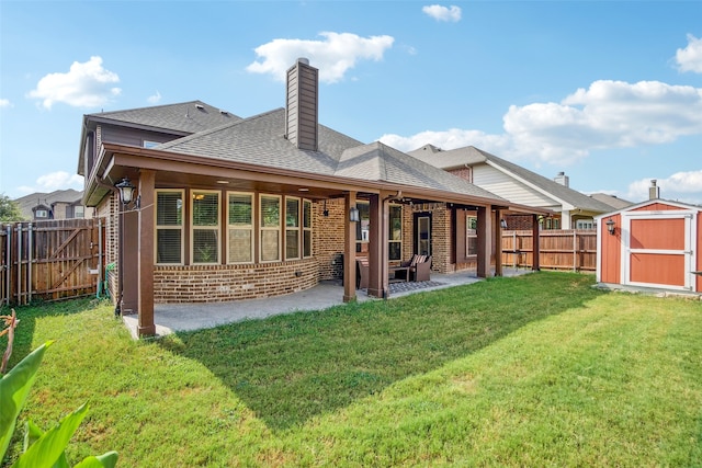 back of property with a shed, a yard, and a patio area