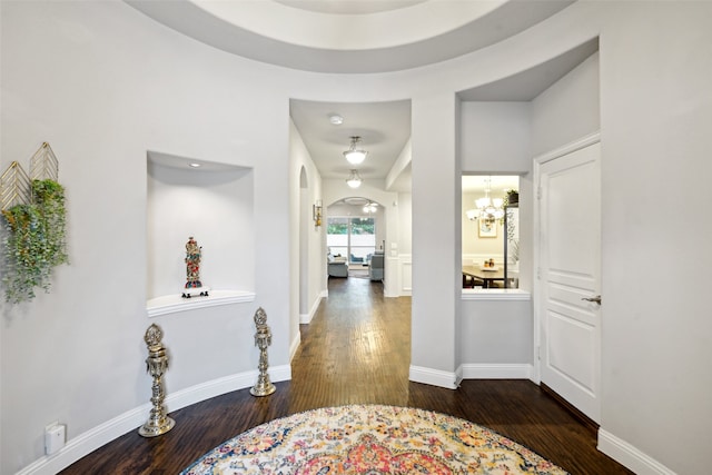 corridor with dark hardwood / wood-style flooring and a chandelier