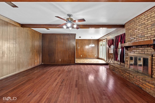 unfurnished living room featuring ceiling fan, beamed ceiling, a brick fireplace, and dark hardwood / wood-style flooring