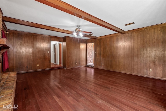 unfurnished living room with a fireplace, beam ceiling, dark wood-type flooring, ceiling fan, and wood walls