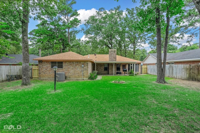 rear view of property featuring central air condition unit and a lawn